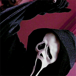 Ghostface from the movie Scream bringing a knife up above his head, as if about to strike. The background is red.